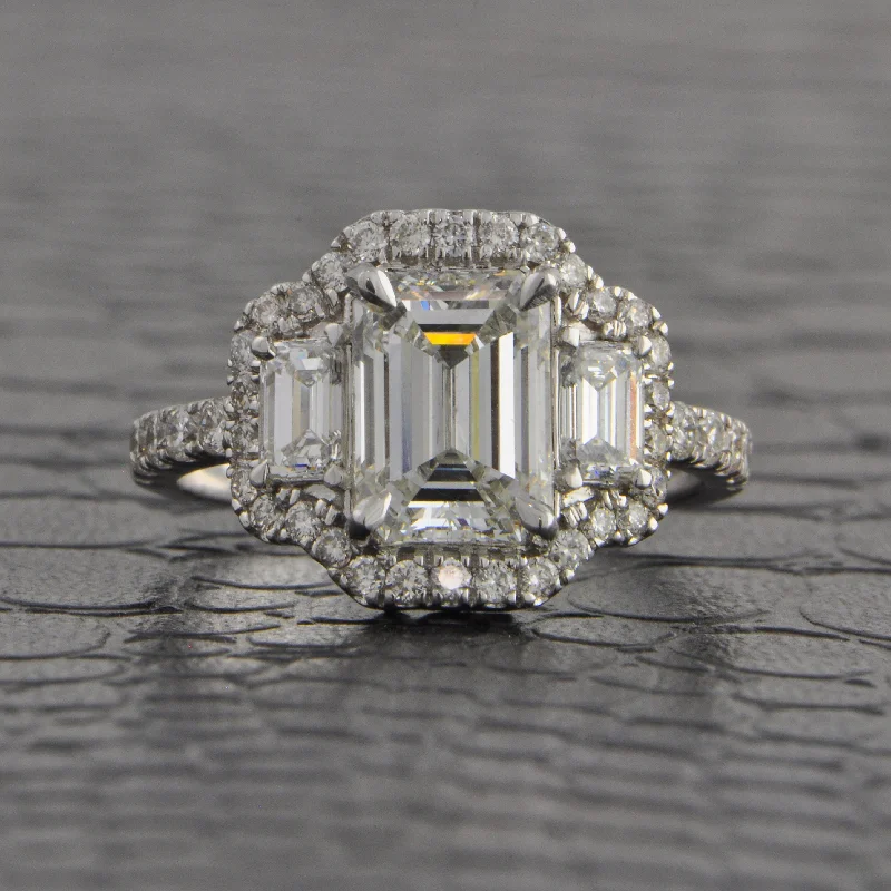 ladies engagement ring openwork-Magnificent Three Stone Emerald Cut Halo Engagement Ring in White Gold